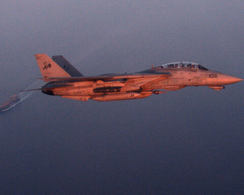 US Navy F-14D Tomcat fighter jet flying over an oil tanker during a maritime security patrol in the Persian Gulf near the Strait of Hormuz