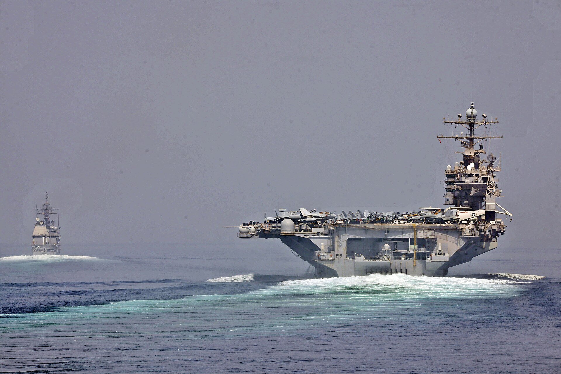 U.S. Navy aircraft carrier and guided-missile cruiser transit the Strait of Hormuz, the vital shipping lane now closed amid the 2026 Iran war. Photo: U.S. Navy / Public Domain