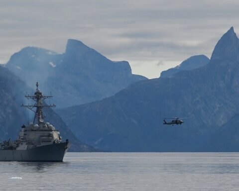 A U.S. Navy Arleigh Burke-class guided-missile destroyer and MH-60R Seahawk helicopter at sea, the type of warship that would lead escort convoys through the Strait of Hormuz. Photo: U.S. Navy / Public Domain