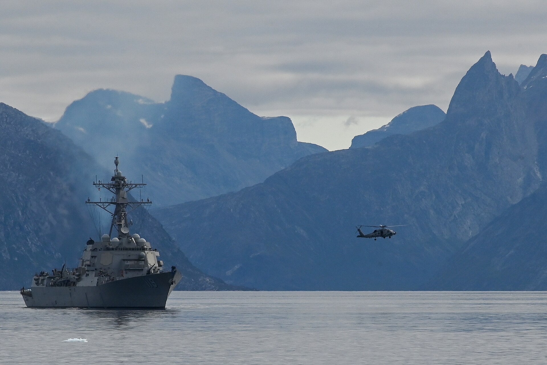 A U.S. Navy Arleigh Burke-class guided-missile destroyer and MH-60R Seahawk helicopter at sea, the type of warship that would lead escort convoys through the Strait of Hormuz. Photo: U.S. Navy / Public Domain