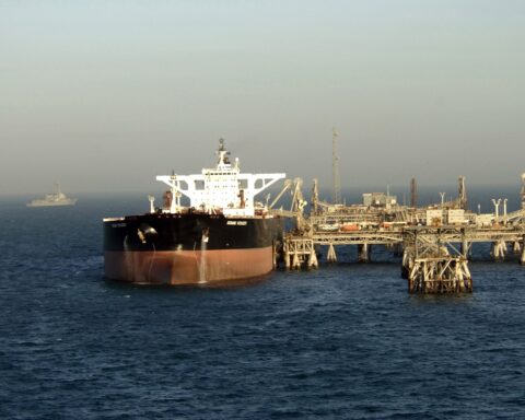 Super oil tanker loading crude at Al Basrah Oil Terminal in the North Arabian Gulf, escorted by US Navy warship