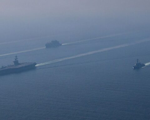 USS Abraham Lincoln carrier strike group in formation at sea, 2026, with escorting destroyers and supply vessel