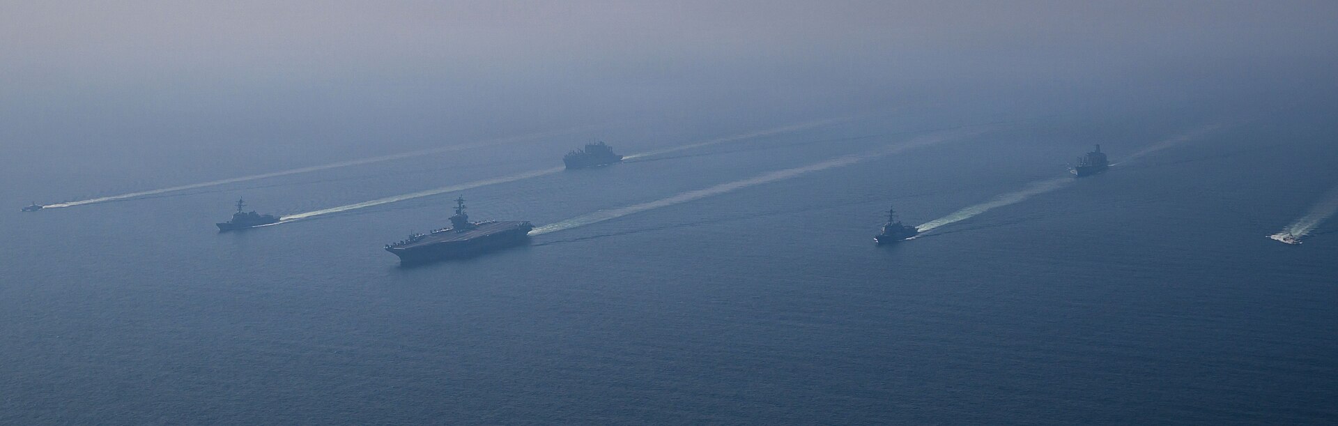 USS Abraham Lincoln carrier strike group underway in the Middle East, 2026, with escort destroyers and replenishment vessel