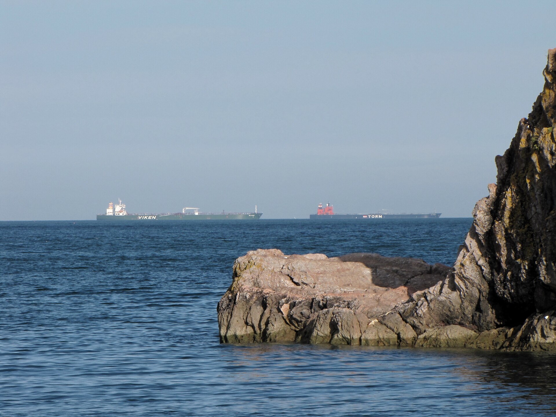 Multiple oil tankers anchored at sea, vessels sitting idle waiting for passage clearance