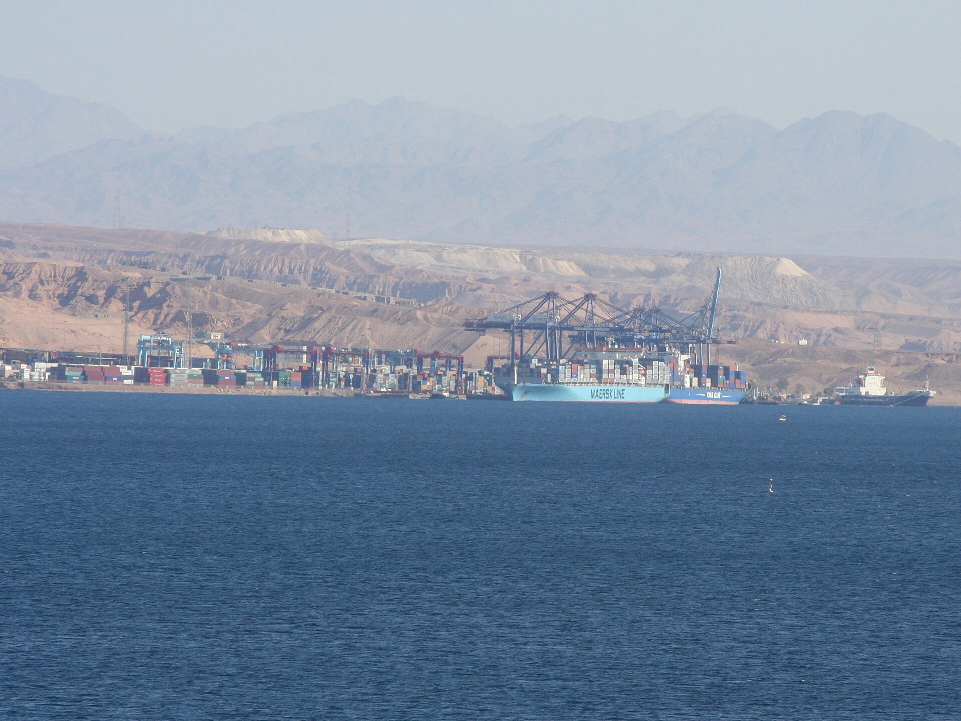 Aqaba container port in Jordan with a Maersk Line vessel berthed at the terminal against the backdrop of desert mountains, key Red Sea logistics node