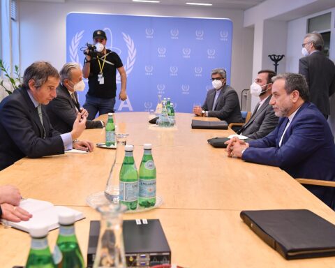 Iranian Foreign Minister Abbas Araghchi in diplomatic talks across a conference table, IAEA backdrop visible, nuclear negotiations setting