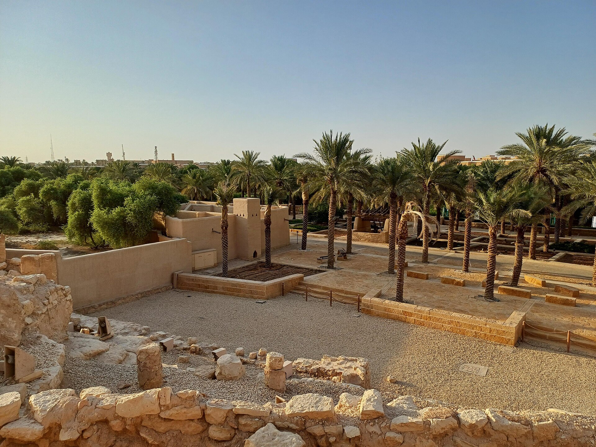 The restored At-Turaif District in Diriyah surrounded by date palms