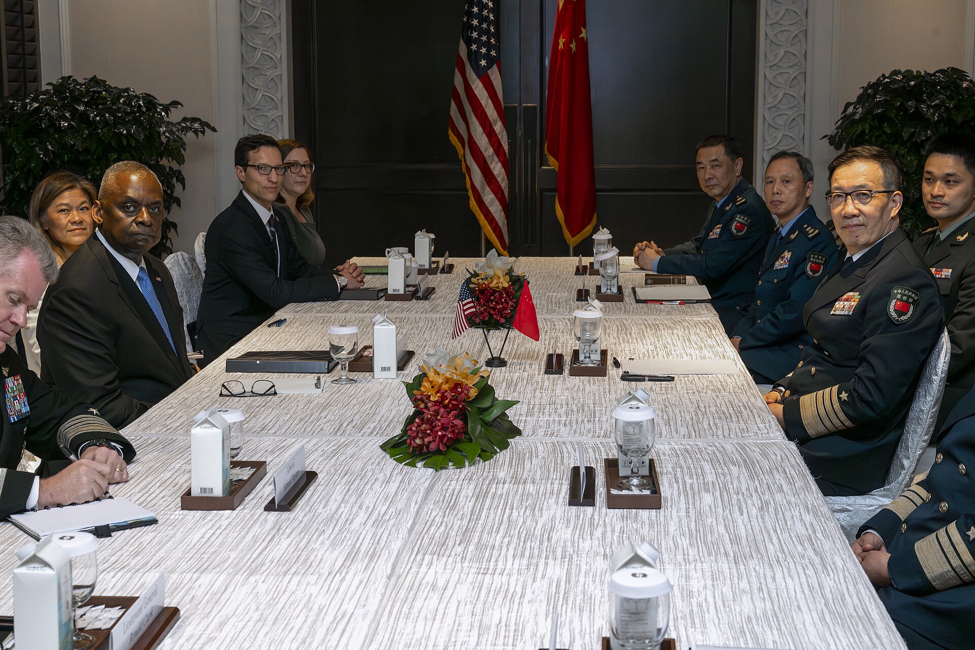 US Secretary of Defense Lloyd Austin and Chinese Defense Minister Dong Jun face each other across a bilateral meeting table in Singapore, May 2024, with US and Chinese flags behind each delegation