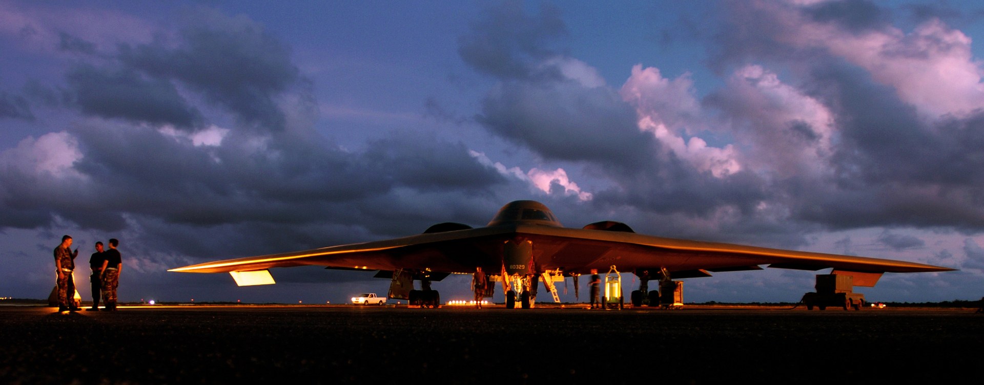 B-2 Spirit stealth bomber being prepared for a mission at Andersen Air Force Base, Guam, at dusk — the only aircraft capable of delivering the GBU-57 Massive Ordnance Penetrator against deeply buried targets like Fordow