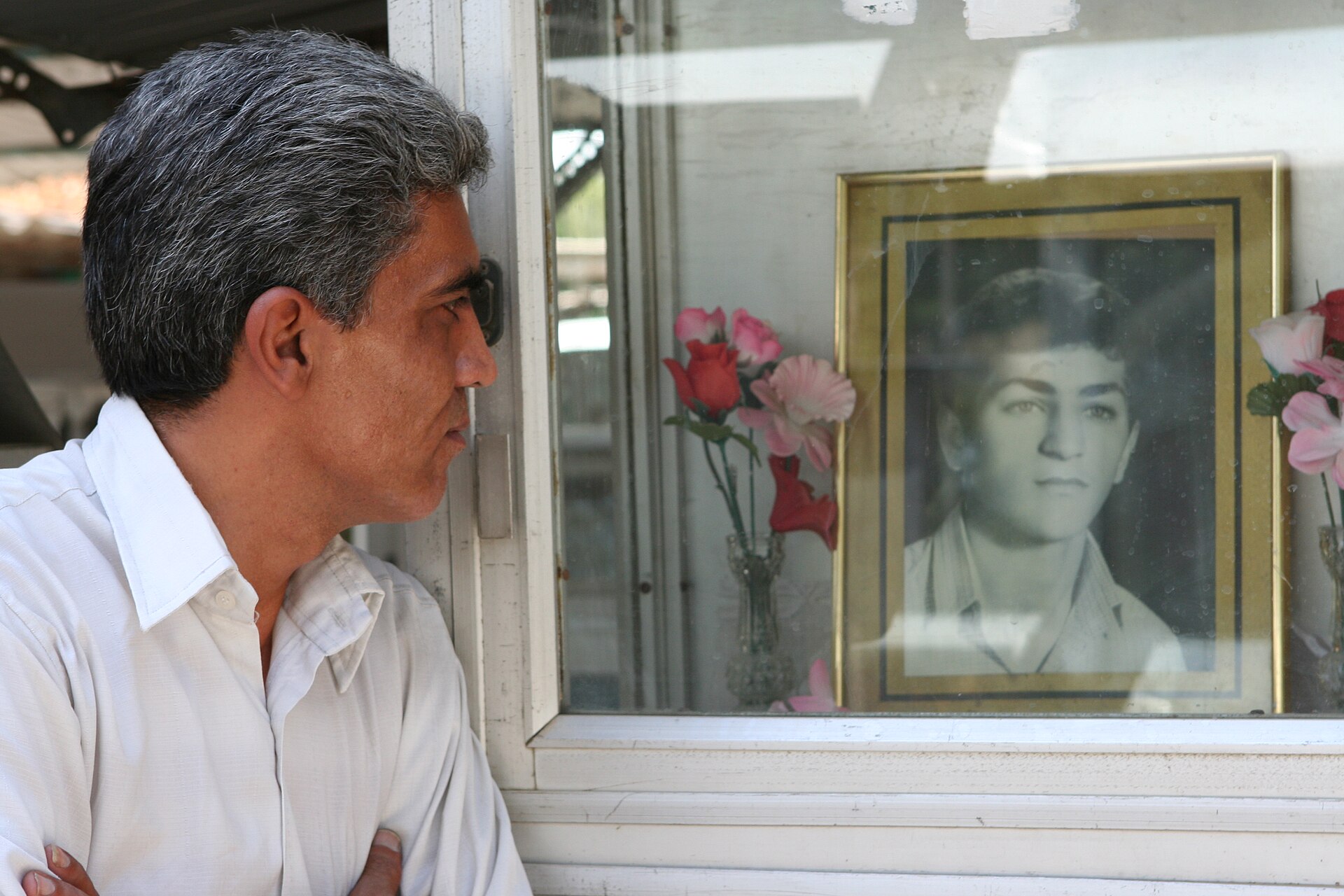 A man at Beheshte Zahra cemetery, Tehran, gazes at the portrait of a martyr of the Iran-Iraq War (1980-1988) — an estimated 500,000 soldiers died before Khomeini accepted UN Resolution 598