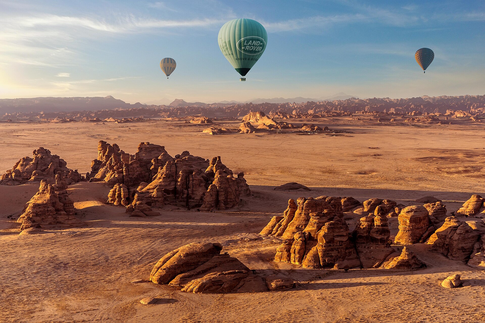 Hot air balloons floating above the sandstone rock formations of AlUla Saudi Arabia