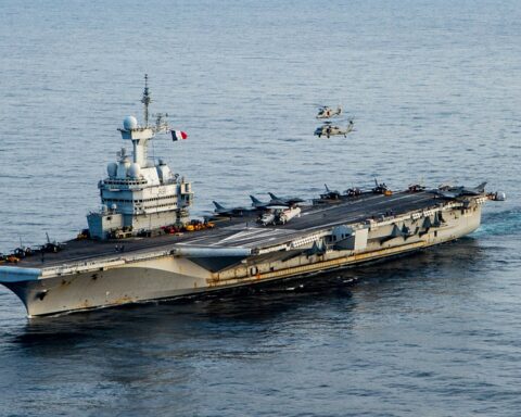 French aircraft carrier Charles de Gaulle (R91) underway in the Ionian Sea on 17 March 2022, with Rafale fighters and helicopters on deck — the only non-American nuclear-powered carrier in operation, positioned for the European Hormuz coalition