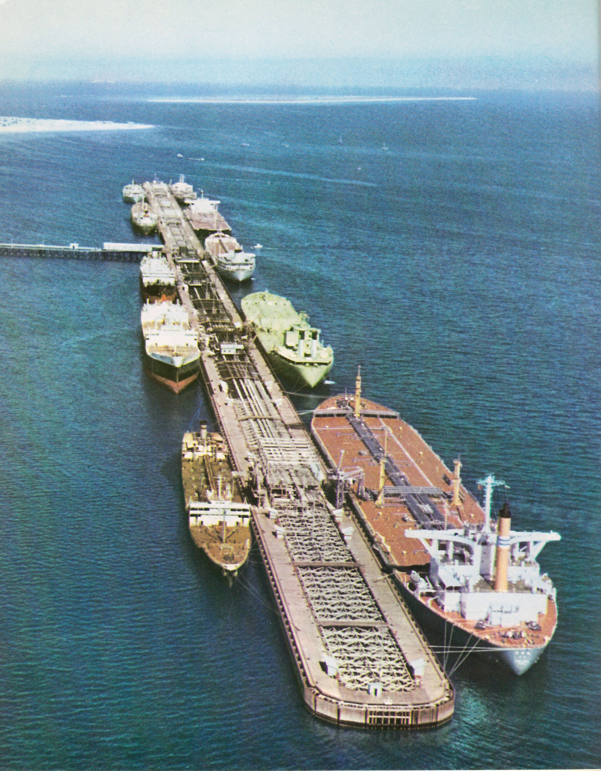 Aerial view of large crude oil tankers loading simultaneously at the Kharg Island oil terminal loading pier, showing multiple vessels berthed at the offshore loading platform