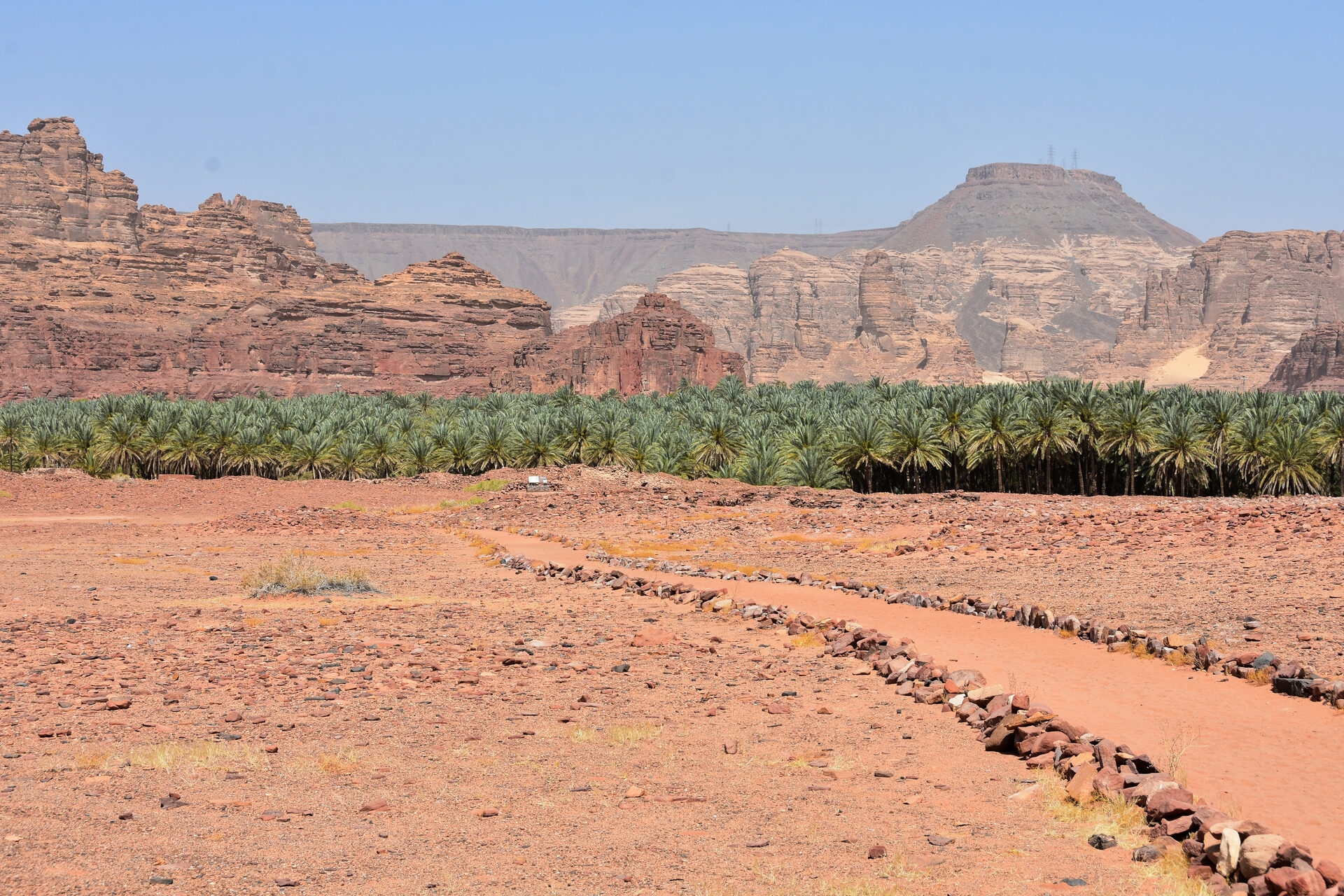 Excavated ruins of the ancient kingdom of Dadan near AlUla, with stone pathways and towering red sandstone cliffs