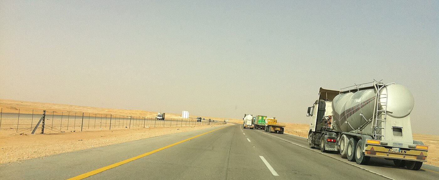 The Dammam-Riyadh highway stretching across the Saudi Arabian desert with trucks on the road