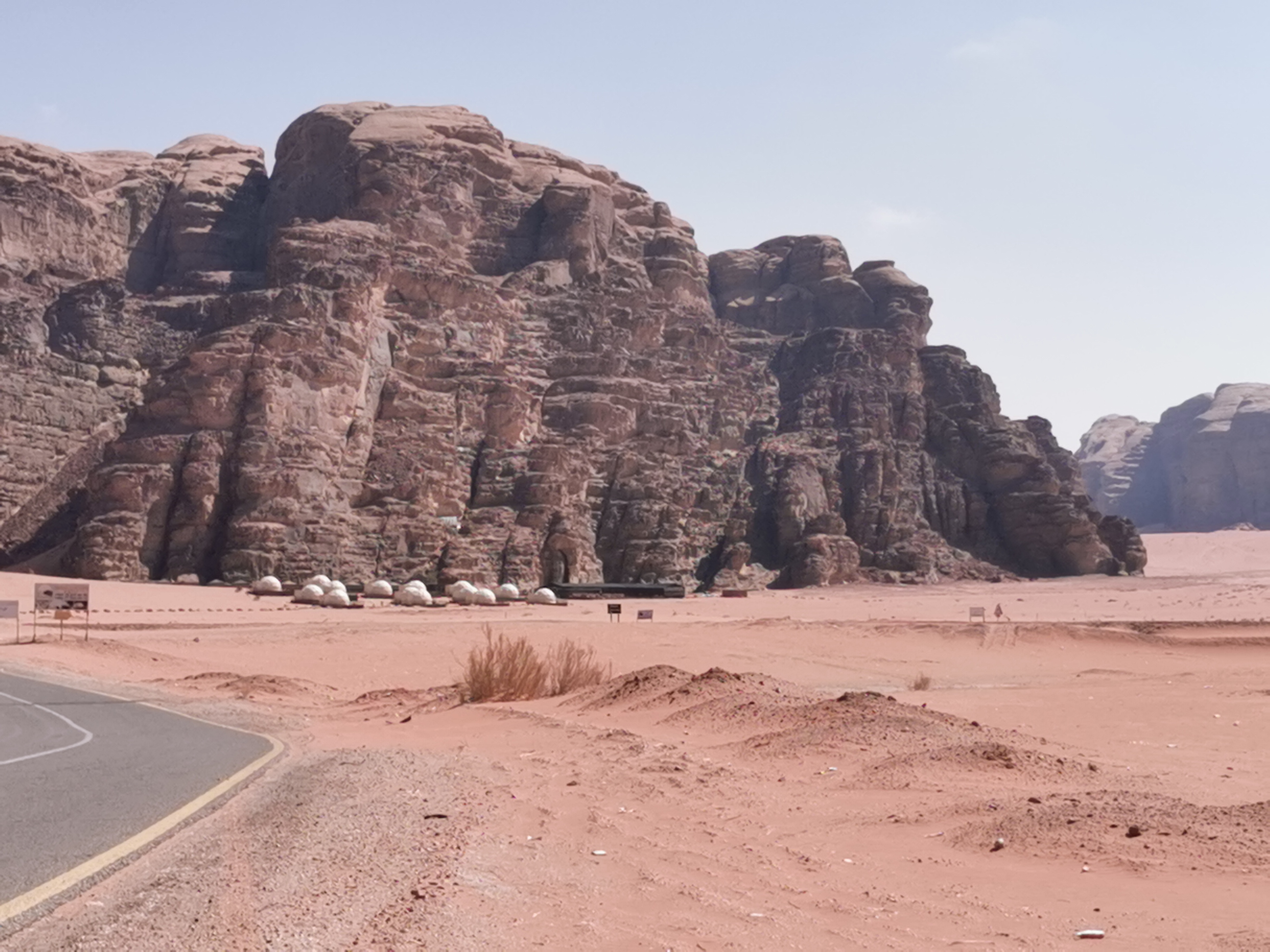 Traditional Bedouin desert camp with goat-hair tents and modern glamping pods against desert mountains