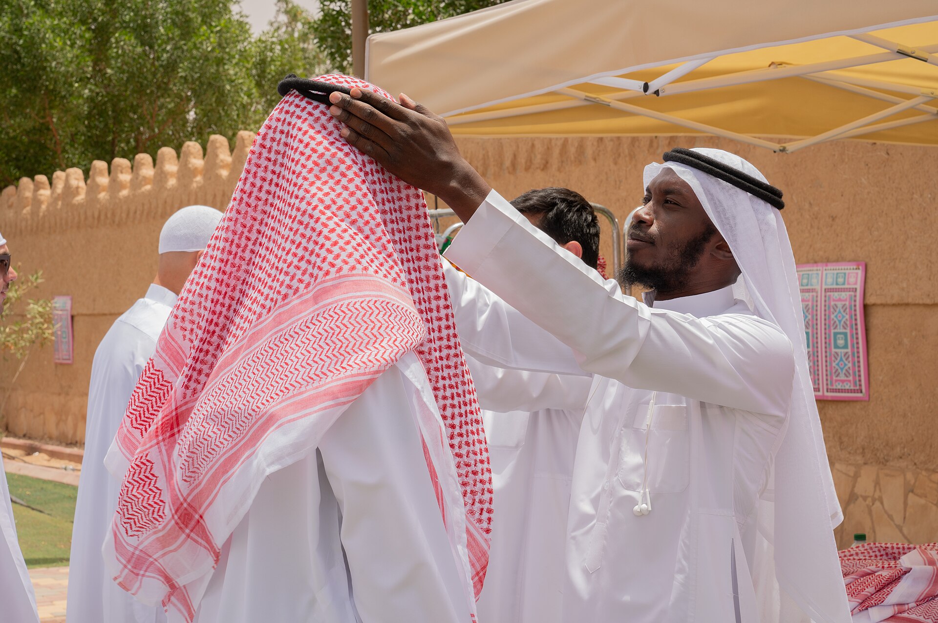Men wearing traditional Saudi thobe and red-and-white shemagh headcovering during a cultural event
