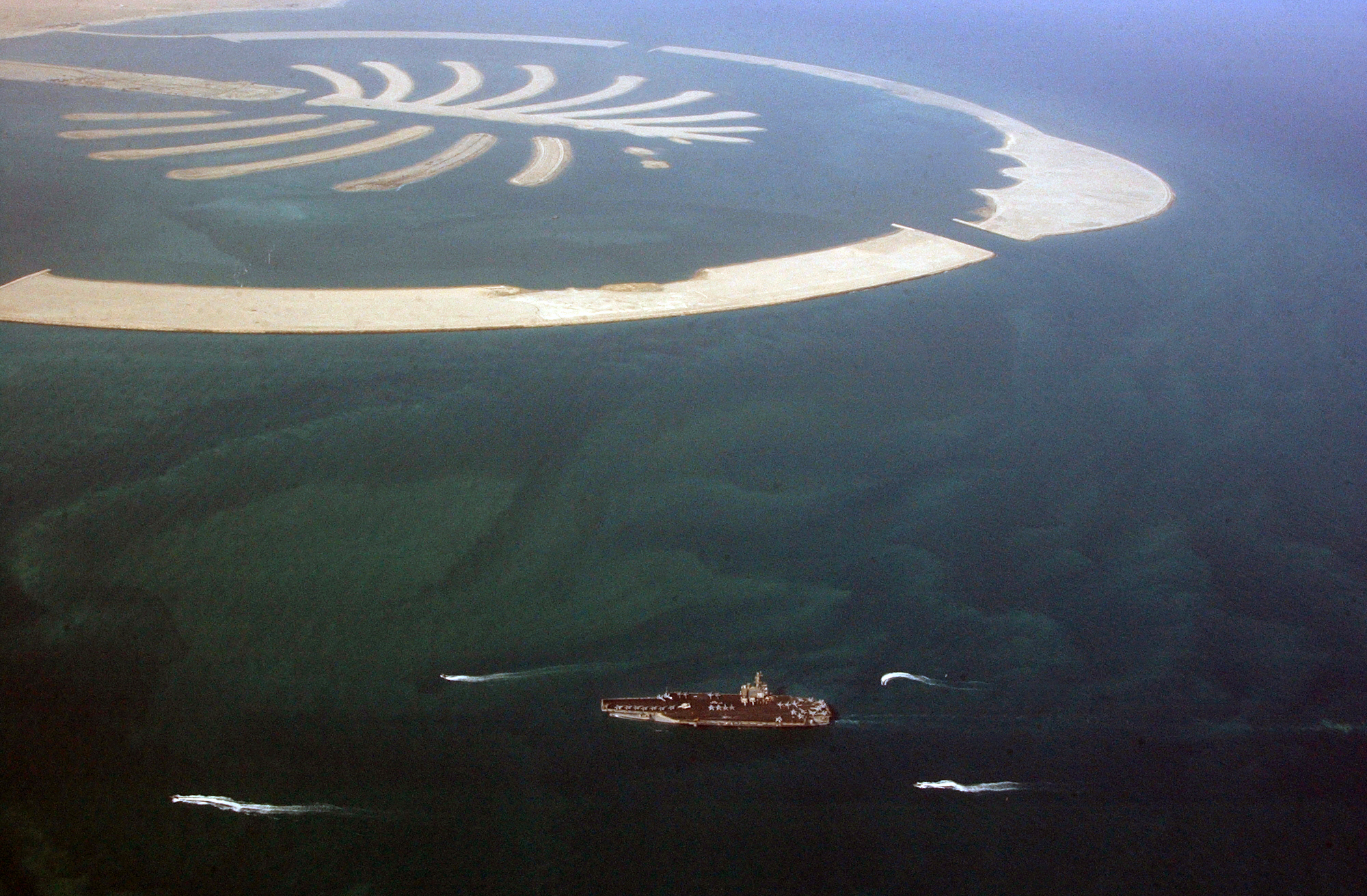 Aerial view of Palm Jumeirah, Dubai, UAE, with USS Ronald Reagan carrier in the Gulf waters below