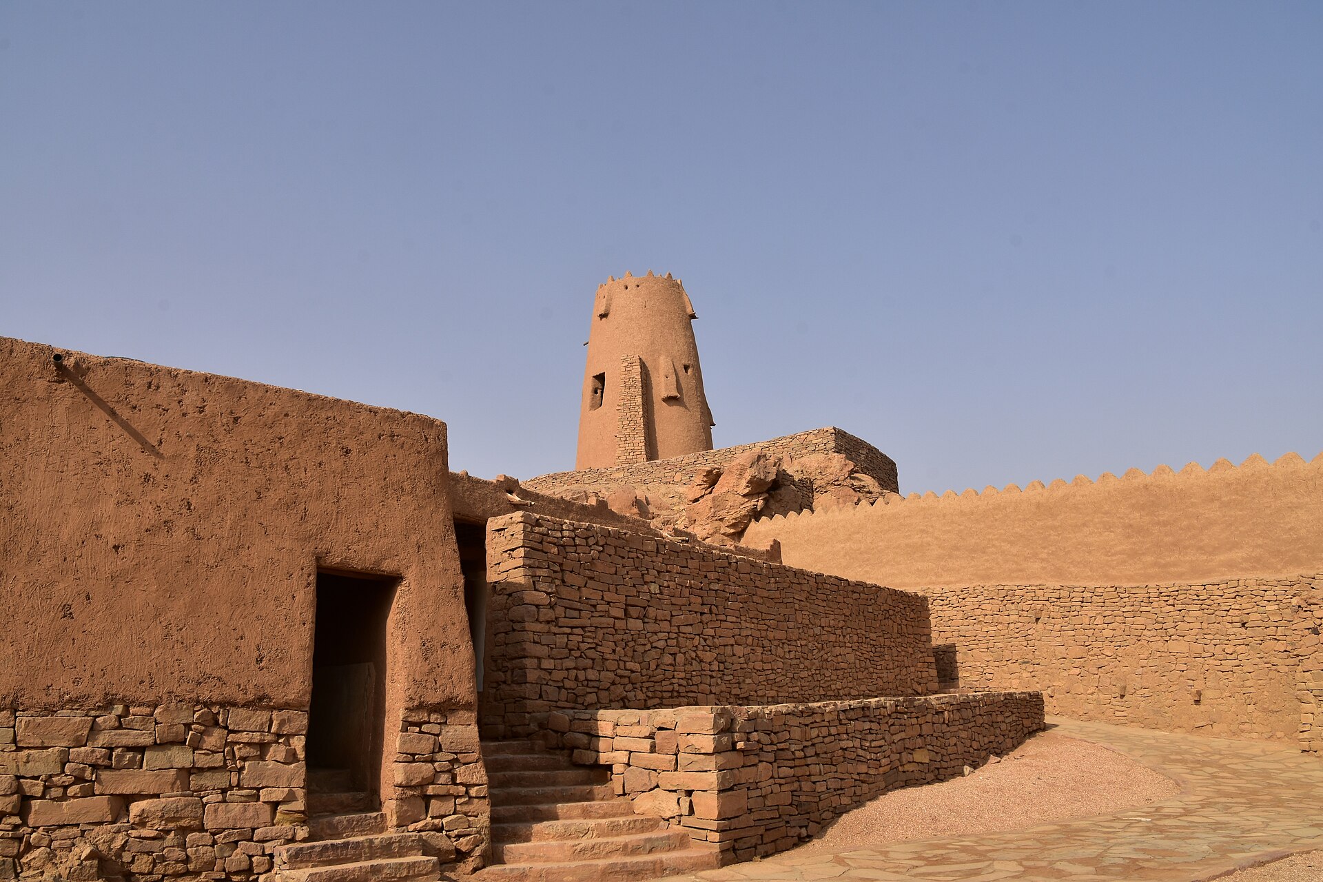 Stone buildings and stairways in the Al-Dari Quarter at Dumat Al-Jandal with Marid Castle tower visible behind