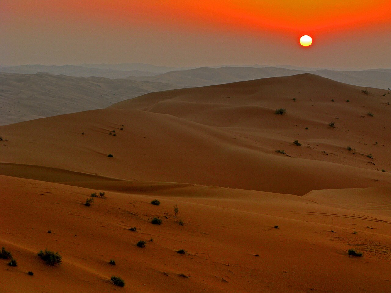 Red and orange sunset over rolling sand dunes of the Rub al Khali empty quarter desert in Saudi Arabia