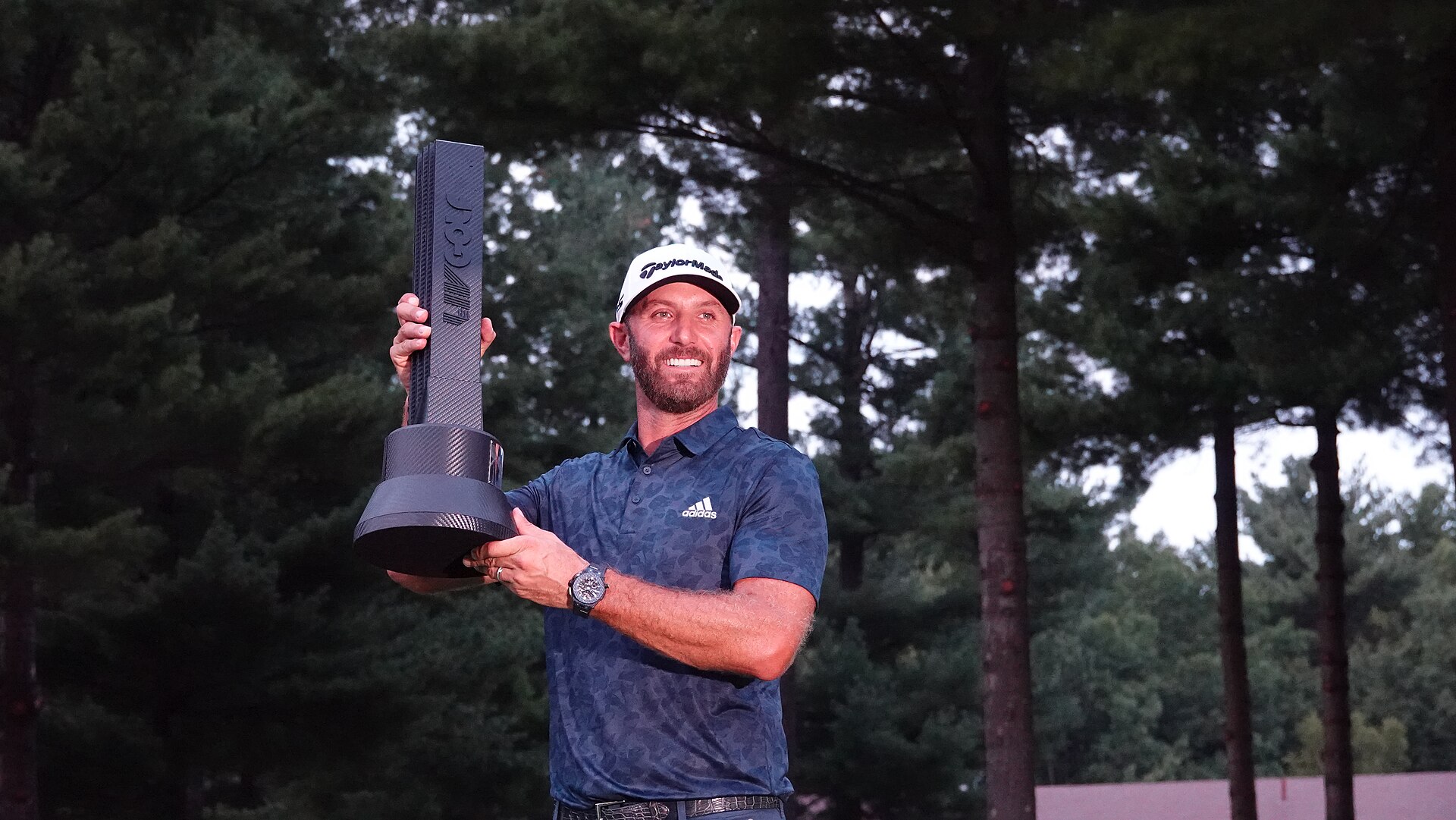 Dustin Johnson holding the LIV Golf championship trophy
