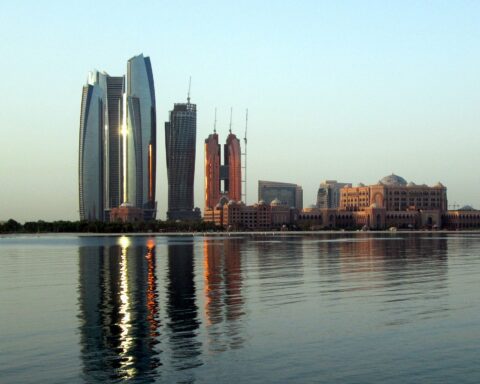 Abu Dhabi skyline with Etihad Towers and Emirates Palace reflected in the water — UAE demanded Iran pay reparations for 2,819 missiles and drones fired at Gulf states