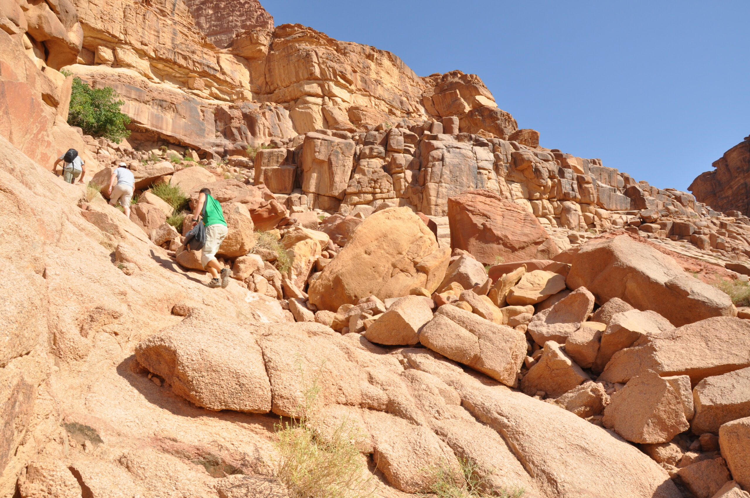 Climbers ascending sandstone rock formations in a desert canyon