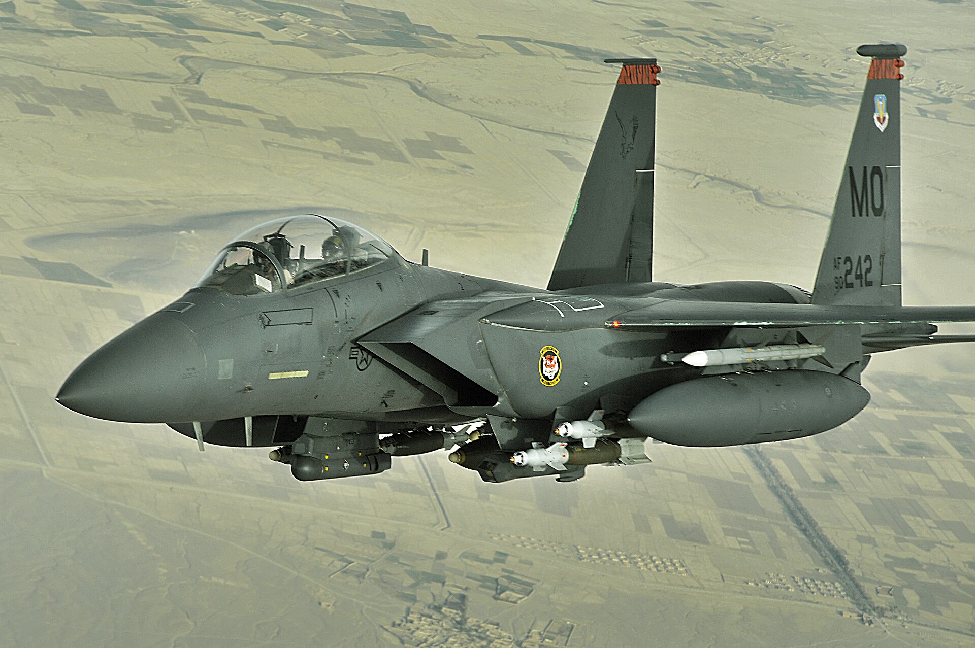 US Air Force F-15E Strike Eagle fully armed with precision munitions flying over Middle East desert terrain