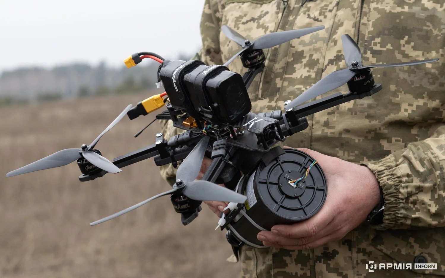 Ukrainian soldier holds a fiber-optic guided FPV drone showing the cable-reel spool that eliminates radio-frequency control links