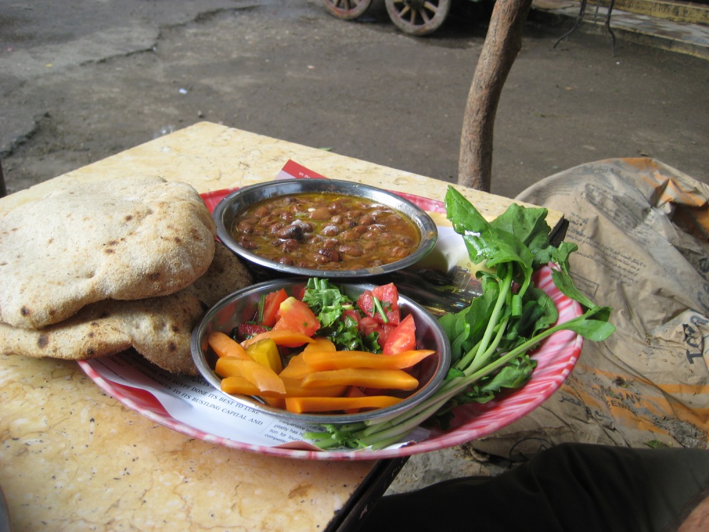 Ful medames fava bean stew served with flatbread and fresh vegetables
