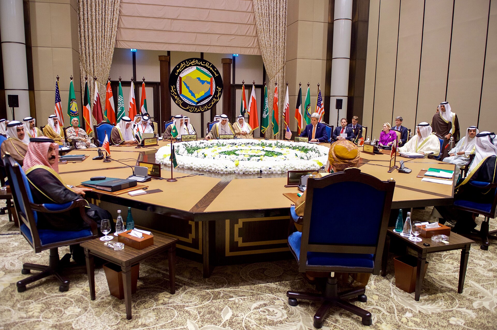 GCC foreign ministers seated at a formal round-table multilateral meeting in Manama, Bahrain, with Gulf Cooperation Council emblem and member state flags