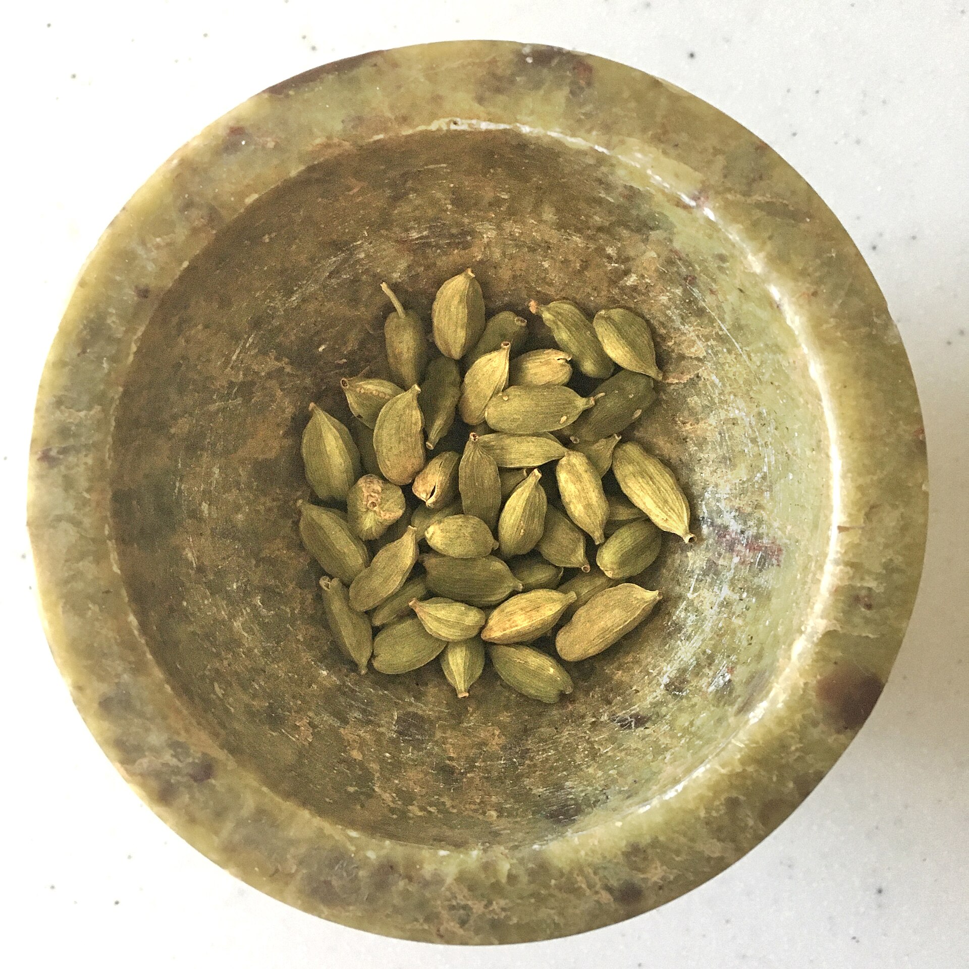 Green cardamom pods in a stone mortar, a staple spice in Saudi Arabian cooking