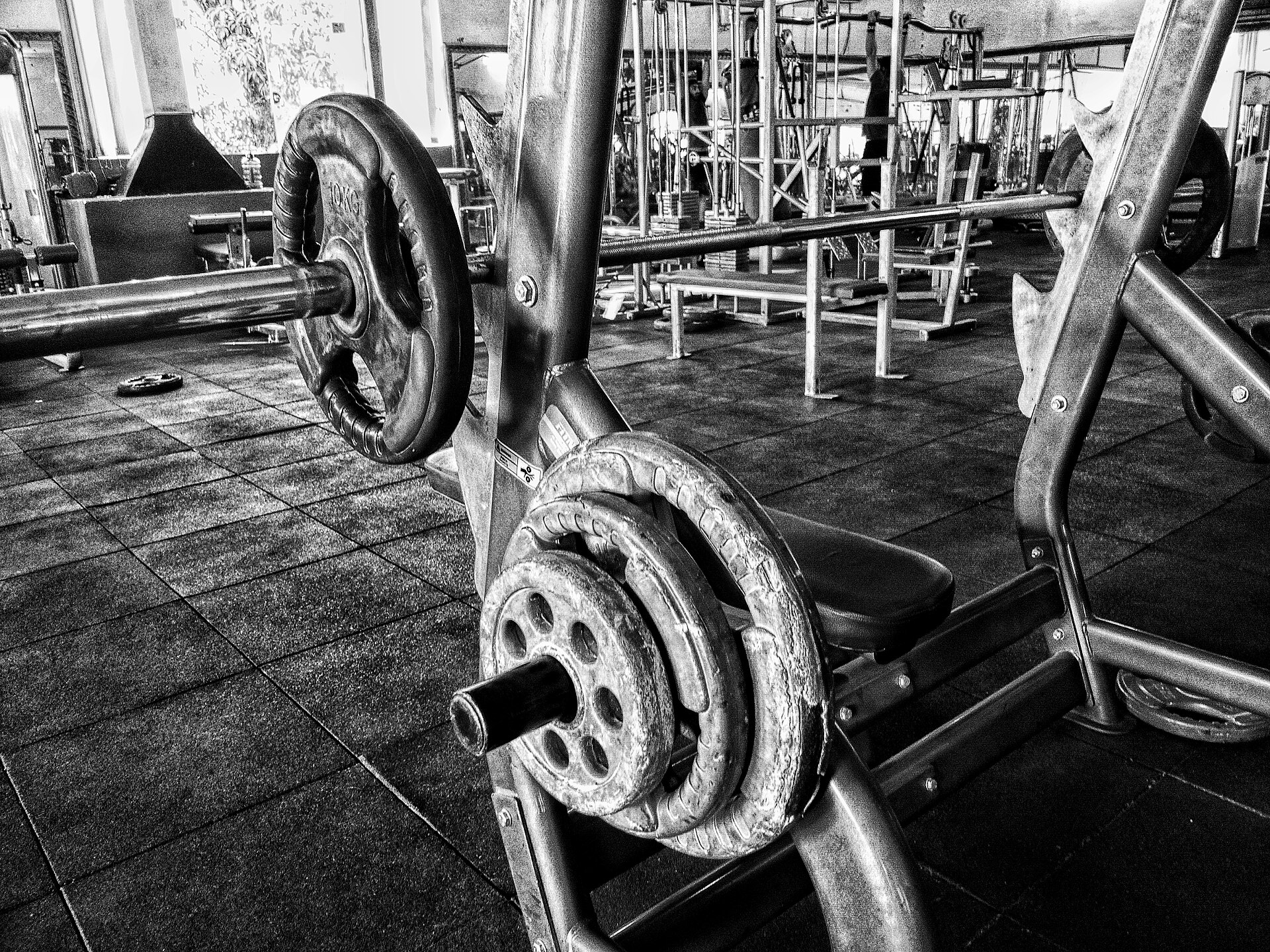 Barbell and weight plates on a bench press rack inside a gym