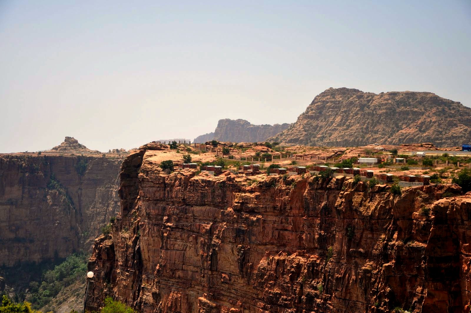 Dramatic cliff face at Habala Valley near Abha showing the hanging village perched on the escarpment rim