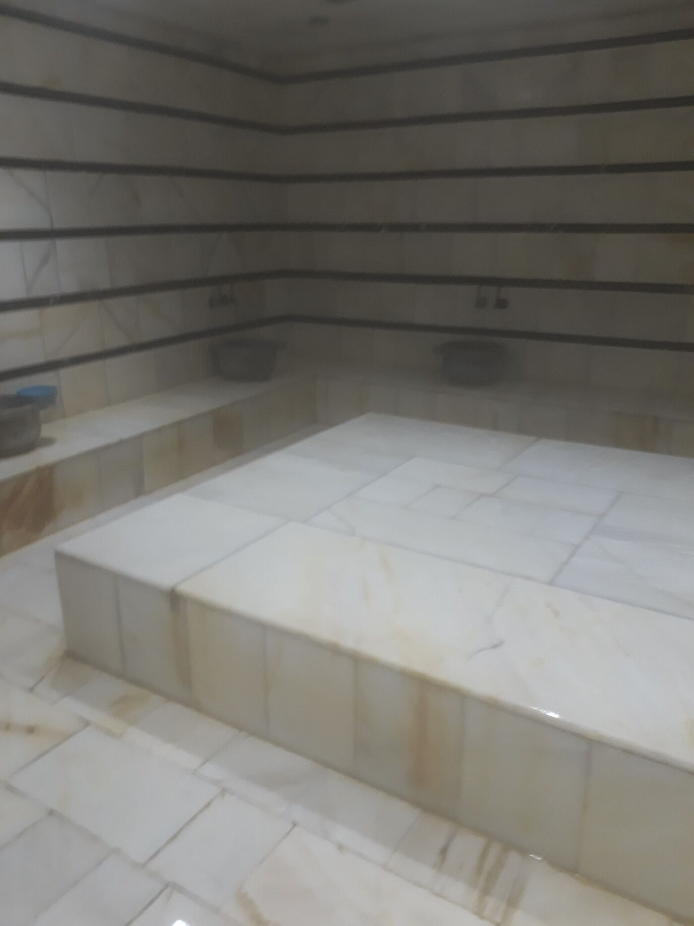 Marble heated platform inside a traditional hammam bathhouse with steam rising from tiled surfaces