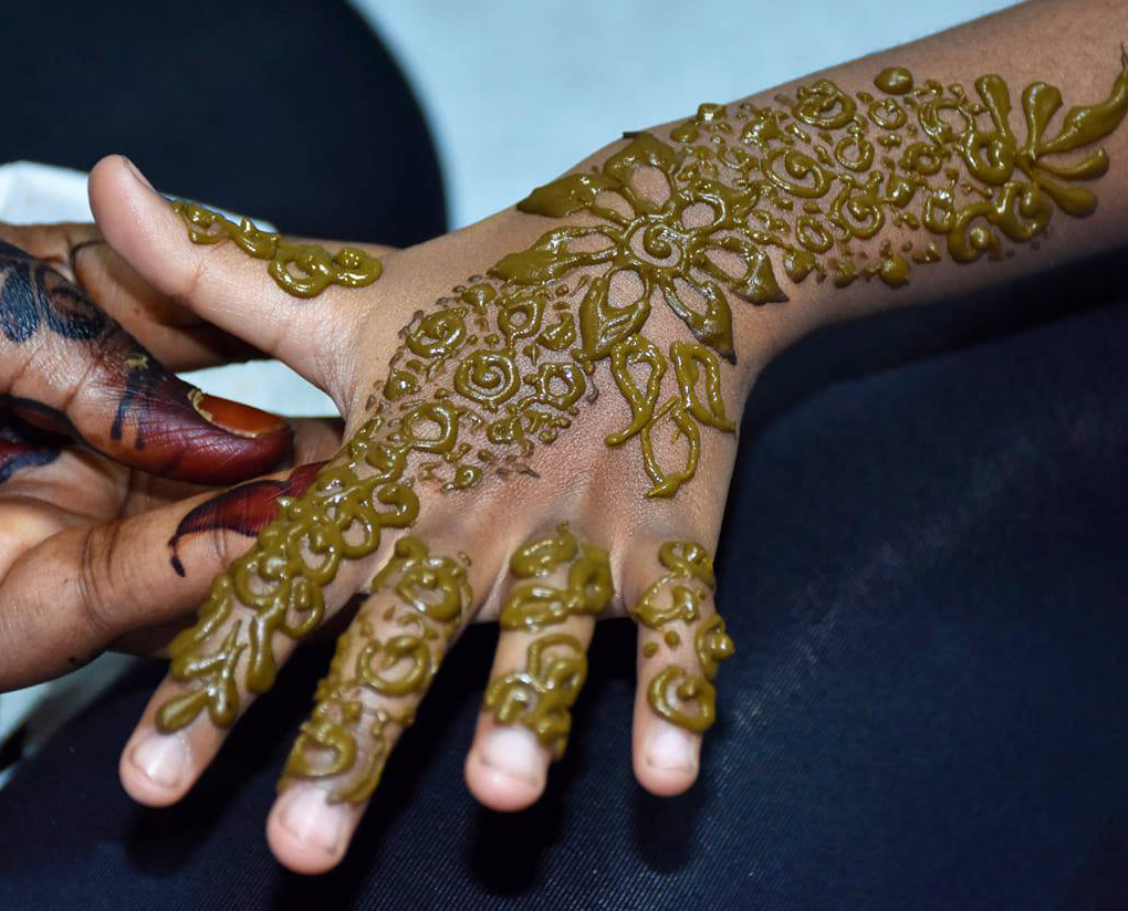 Intricate henna designs being applied to a bride's hand during wedding preparations