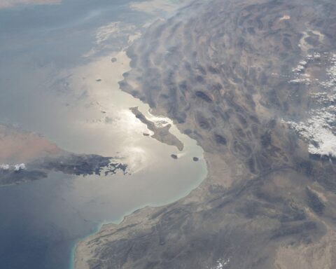 Aerial view of the Strait of Hormuz and Musandam Peninsula from the International Space Station, showing the narrow chokepoint between Iran and Oman through which 20 percent of global oil trade transits