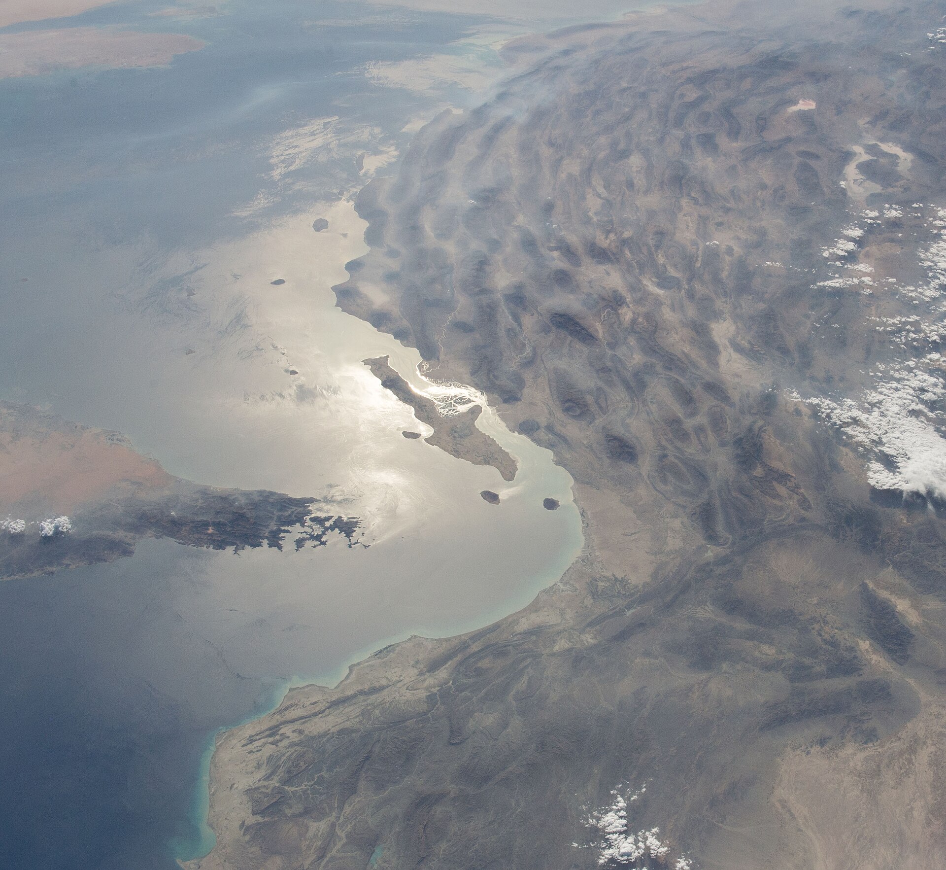 Aerial view of the Strait of Hormuz and Musandam Peninsula from the International Space Station, showing the narrow chokepoint between Iran and Oman through which 20 percent of global oil trade transits