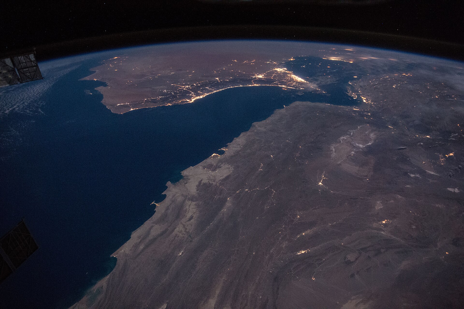 Gulf of Oman and Strait of Hormuz at night from the International Space Station, showing city lights of Muscat, Dubai, Abu Dhabi and Doha along the contested shipping corridor