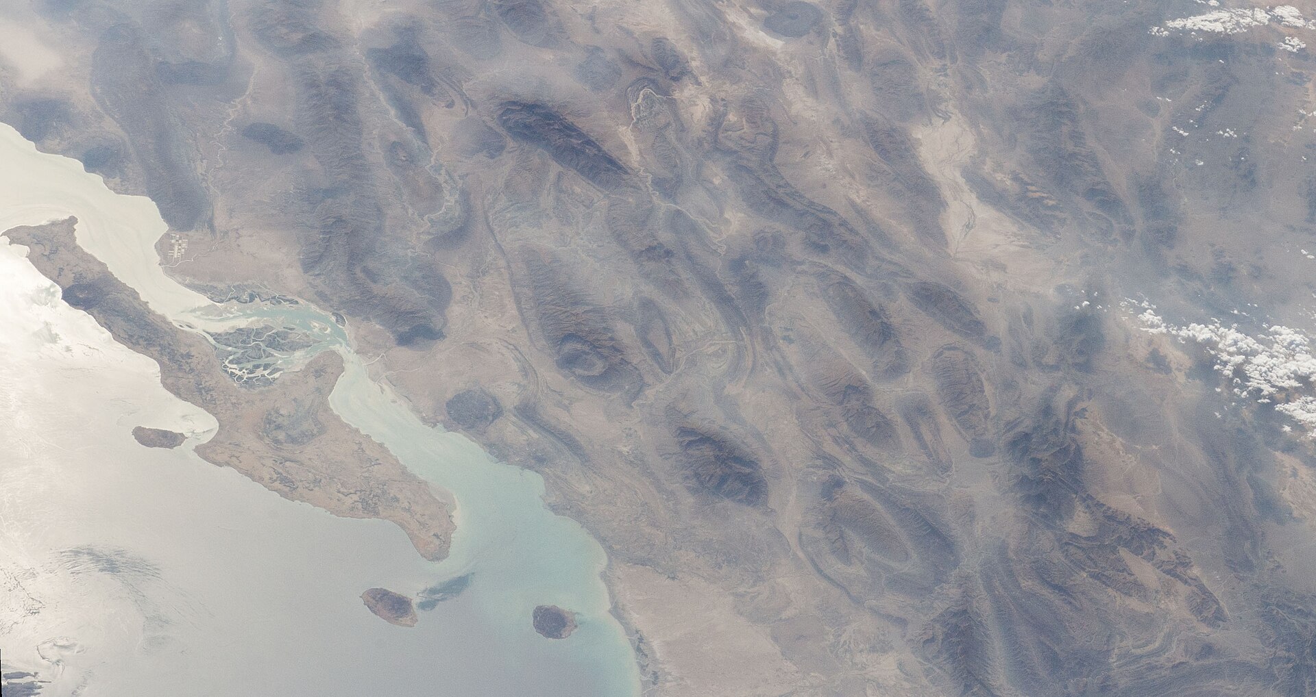 ISS photograph of the Strait of Hormuz showing Qeshm Island and Larak Island, site of the IRGC-designated 5-nautical-mile transit corridor declared in February 2026