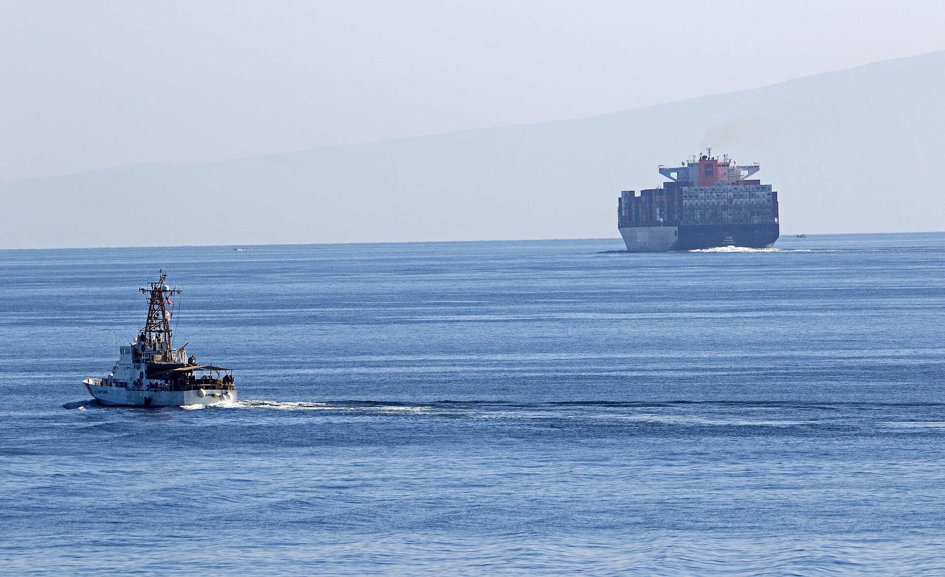 US Coast Guard cutter USCGC Aquidneck transiting the Strait of Hormuz alongside a loaded container ship, December 2, 2020