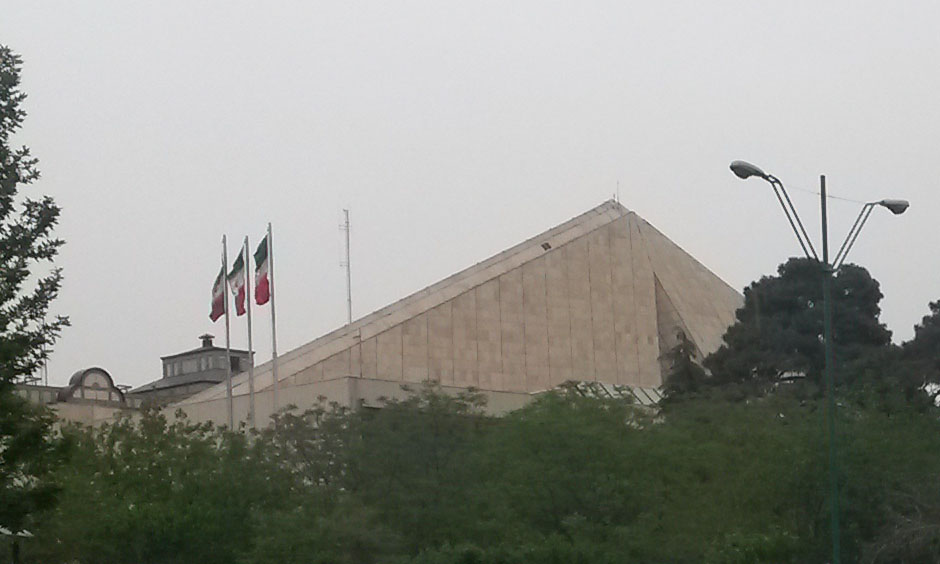 Islamic Consultative Assembly building in Tehran, the Iranian parliament known as the Majlis, with Iranian flags flying from its distinctive pyramid-shaped roof