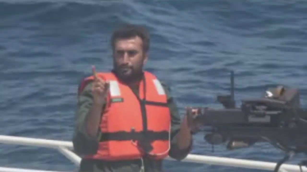 IRGC Navy gunman on patrol boat pointing warning at US Navy warship in Persian Gulf, illustrating the type of fast-attack craft that approached the Sanmar Herald