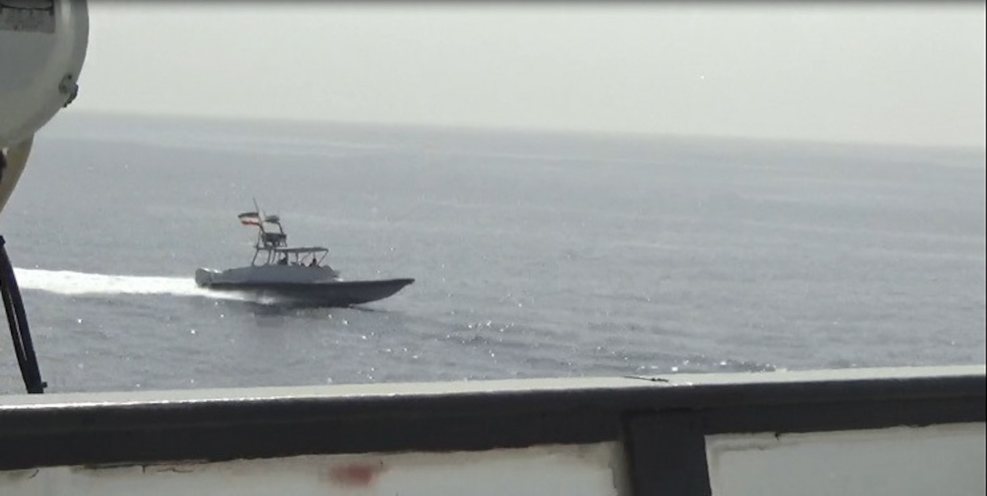 An Iranian IRGC Navy fast attack craft bearing the Iranian flag approaches a US naval vessel in the Persian Gulf. IRGC field units operate under a command chain that runs to the Supreme Leader, not the foreign ministry