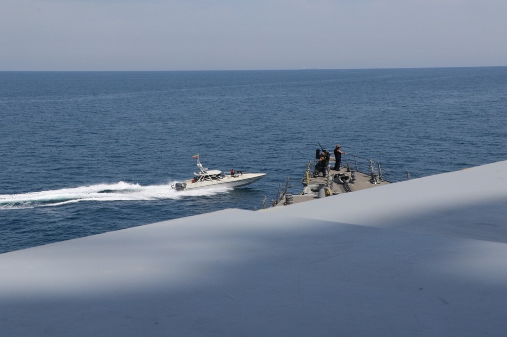 IRGC speedboat flying Iranian flag approaches US Navy vessel in the Arabian Gulf on April 15 2020, with US Navy gunner visible on deck