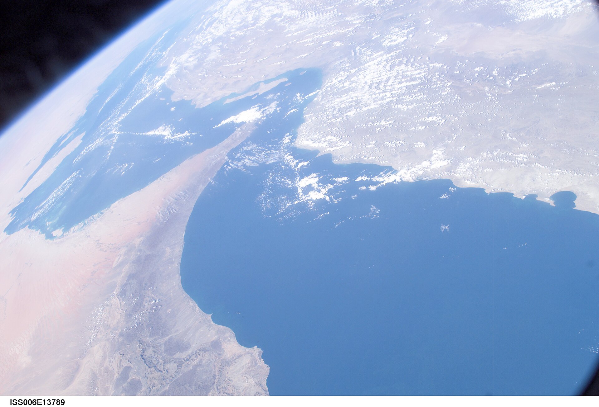 ISS Expedition 6 orbital photograph showing the Persian Gulf, Strait of Hormuz and Gulf of Oman from space. The narrow chokepoint between Iran and Oman handles approximately 21 percent of global oil trade.