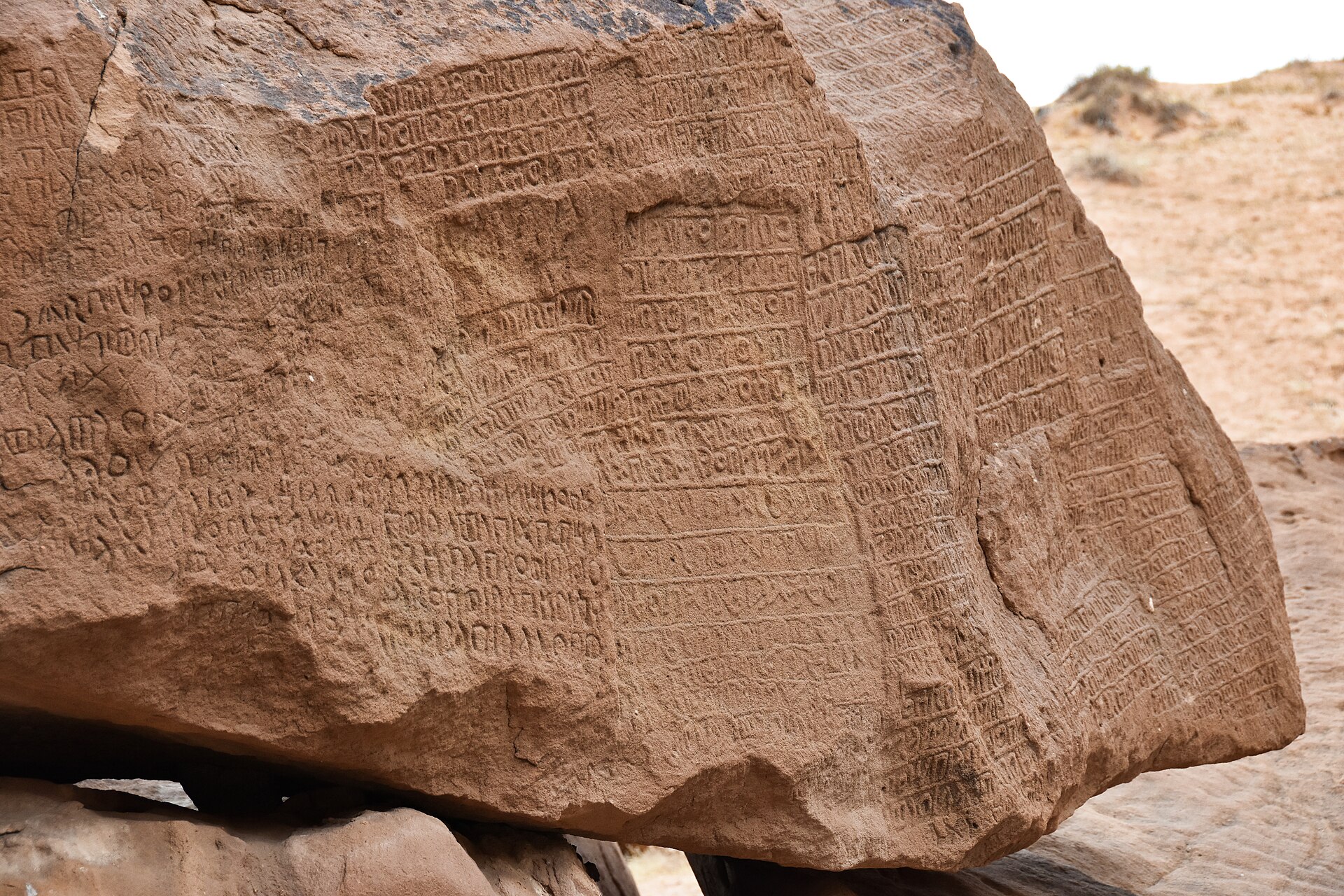 Sandstone rock face at Jabal Ikmah covered in ancient Dadanitic inscriptions carved into the cliff