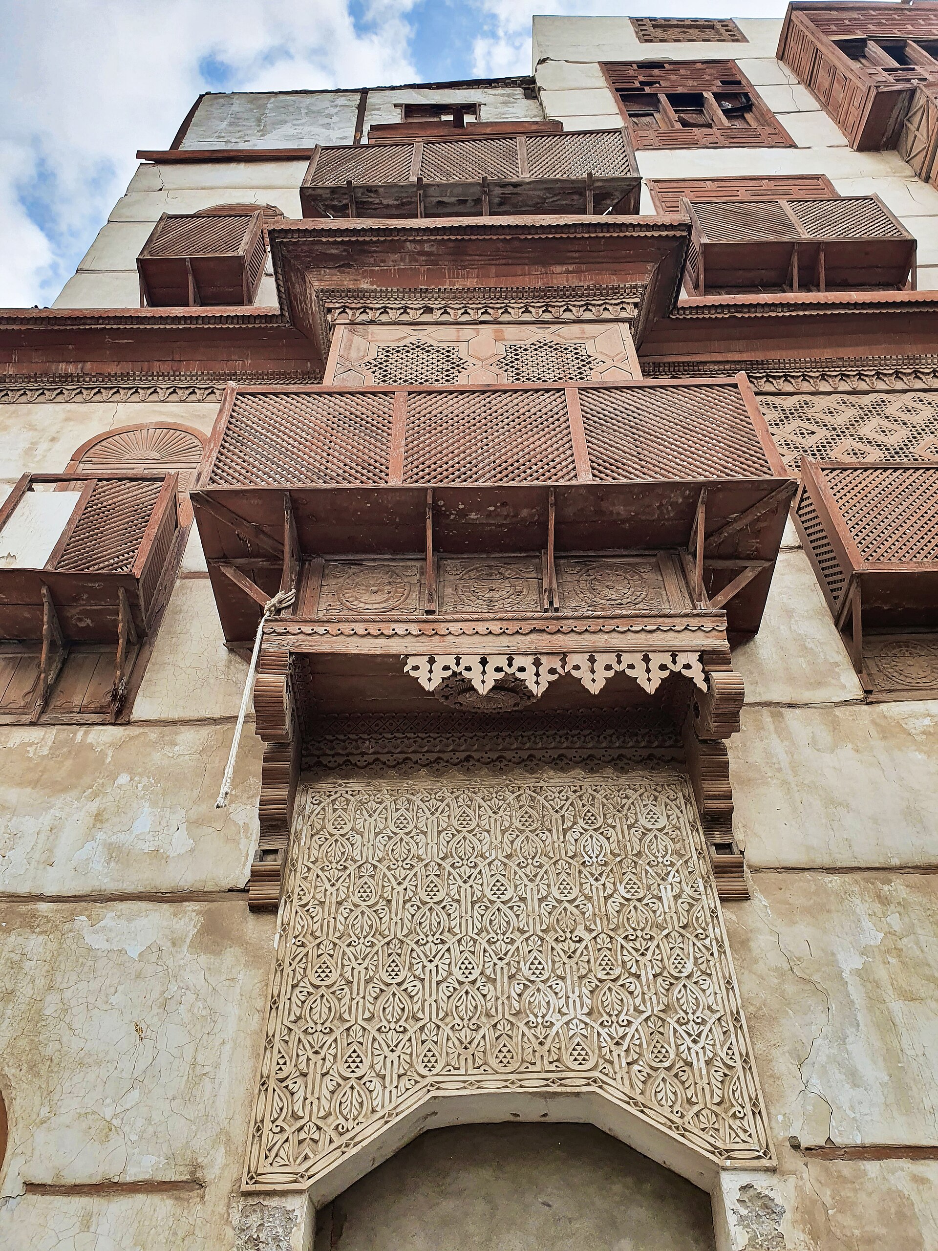 Traditional coral stone building with ornate wooden rawasheen balconies in Al Balad historic district, Jeddah