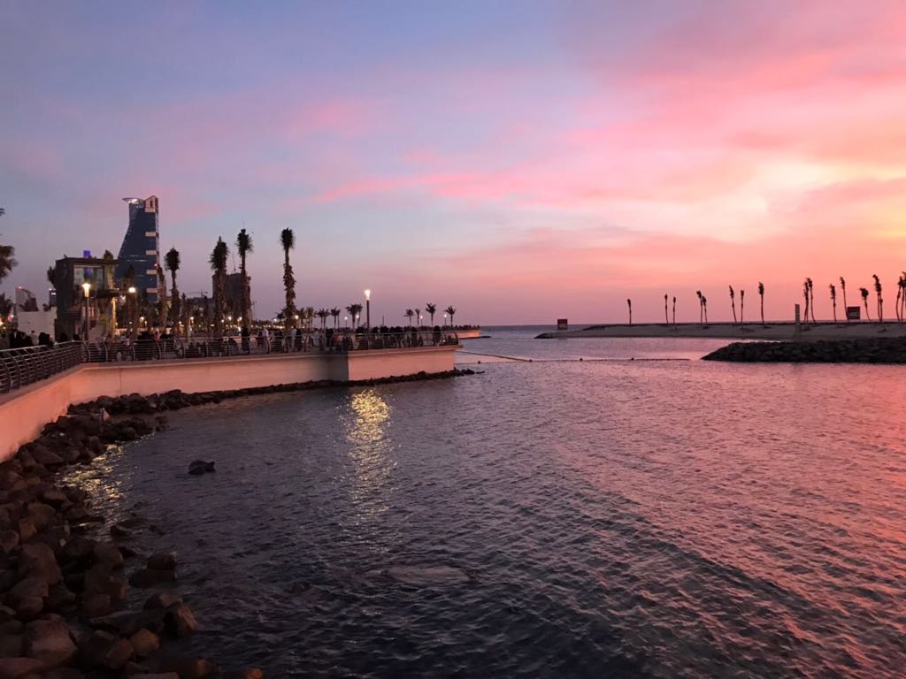 Jeddah Corniche waterfront at sunset with modern skyline and palm trees along the Red Sea