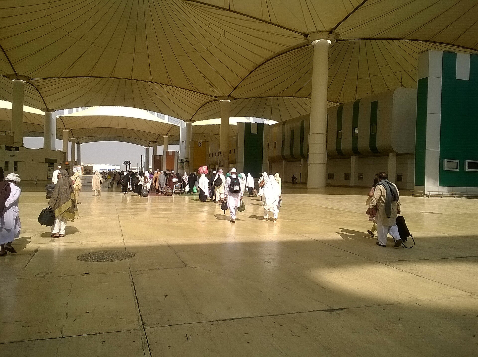 Hajj pilgrims in white ihram walking through the distinctive tent-canopy Hajj Terminal at King Abdulaziz International Airport in Jeddah